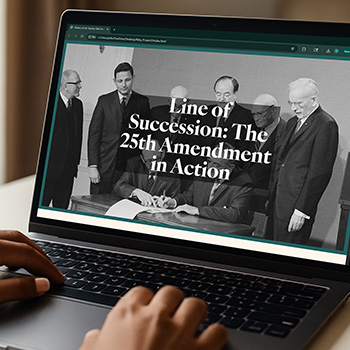 a hand on a laptop with a webpage showing the signing of the 25th amendment