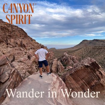 a man standing on top of a red mountain with the logo for Canyon Spirit and the text wander in wonder